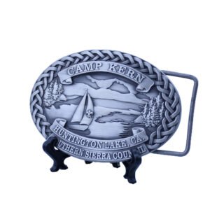 Oval antique silver-tone Camp Kern belt buckle with a sailboat, mountain lake scene and braided border