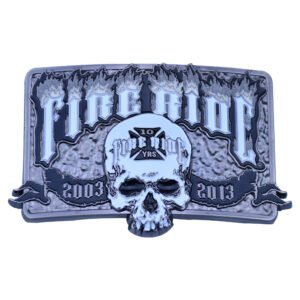 Rectangular silver-tone belt buckle with a raised skull, flame lettering and commemorative dates.