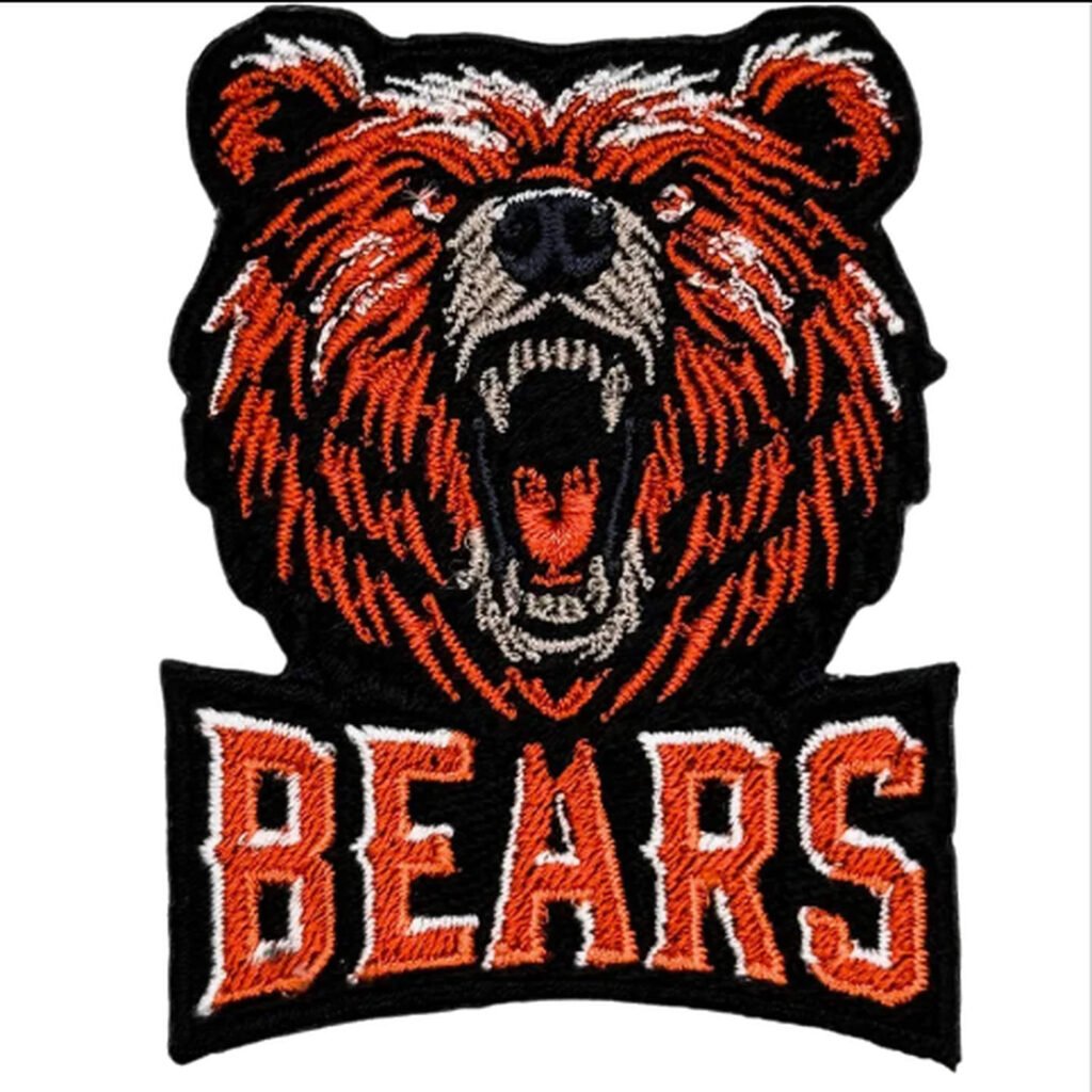 Emblema bordado de um urso rugindo nas cores laranja, preto e branco, com as letras “BEARS” em tamanho grande abaixo da cabeça.
