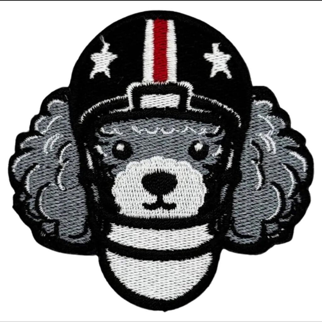 Emblema bordado de um poodle cinza usando um capacete de futebol americano preto com estrelas brancas e uma faixa vermelha no meio.