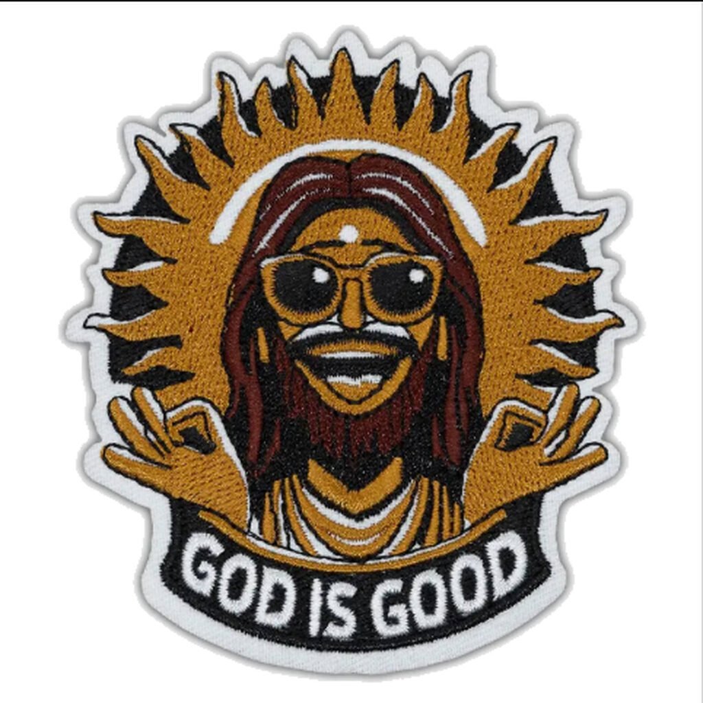 Emblema bordado com a inscrição “GOD IS GOOD”, apresentando uma figura sorridente de óculos escuros, um raio de sol dourado e uma borda branca.